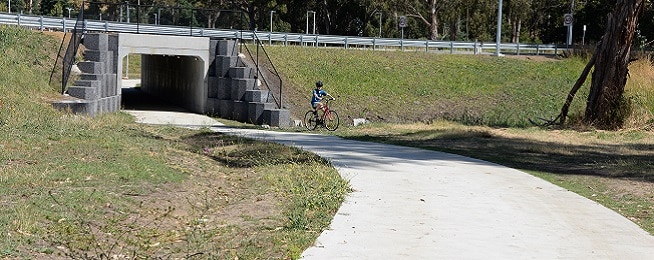 A young child rides through an underpass under the Huon Hwy on the Whitewater Creek path.
